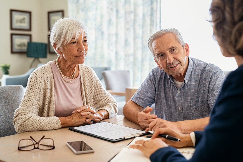 Two elderly people at a funeral arrangement meeting with a funeral director in a funeral home office 