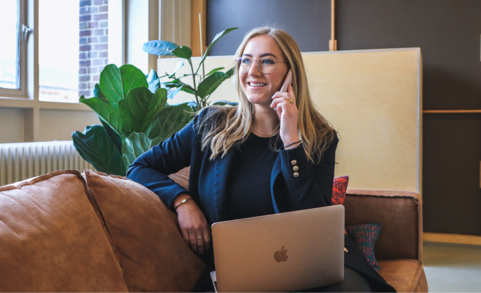 A funeral business professional on the phone sitting on a couch in a funeral home office 