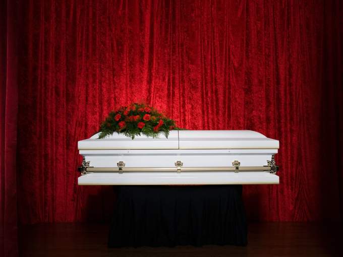 Flowers on a coffin with red curtains in the background 
