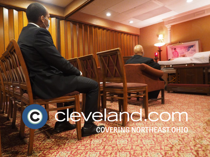 Two grieving family members at a funeral service in a funeral home with an open casket 