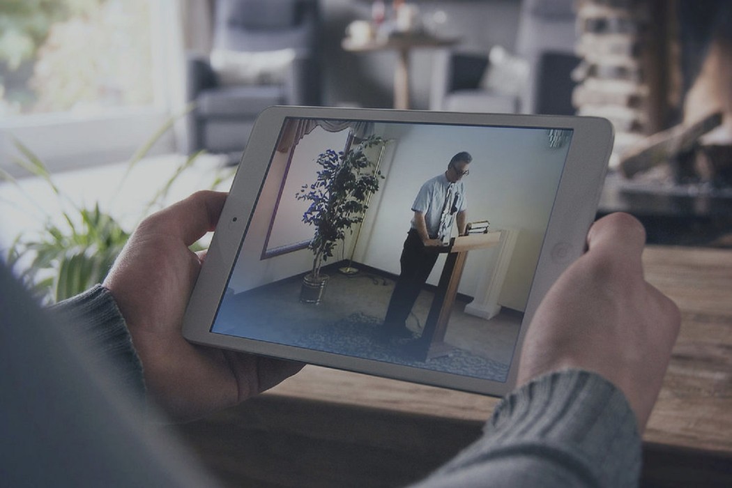 A person holding a tablet watching a celebrant speak at funeral service in a funeral home on the OneRoom platform